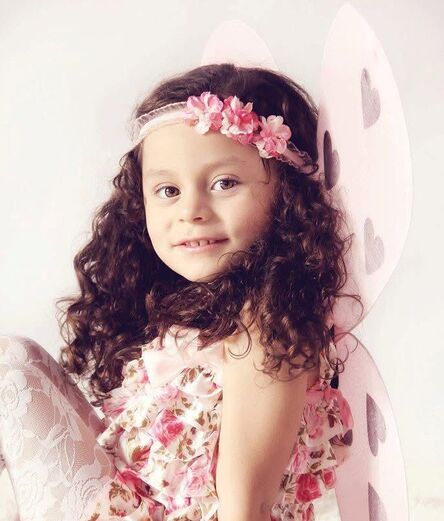 Girl wearing a floral headband and dress with fairy wings