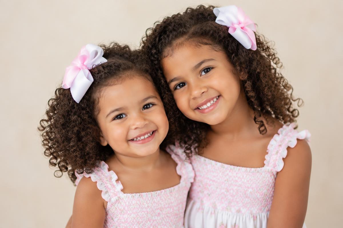 Two sisters wearing matching pink and white bows